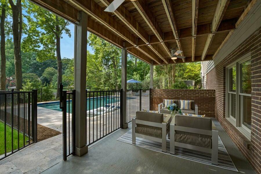 outdoor seating area next to in ground pool with tall safety gate surrounding it at a StayLakeNorman luxury vacation rental