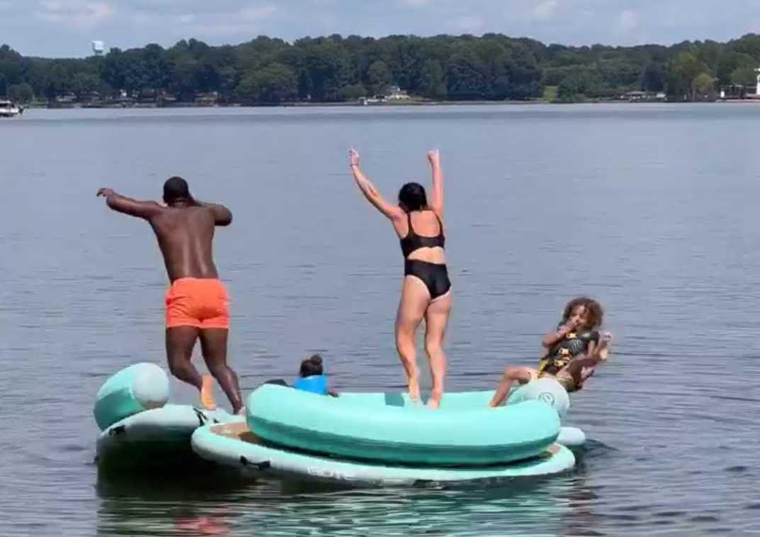 Family playing on giant lake floats and jumping into Lake Norman, NC. 