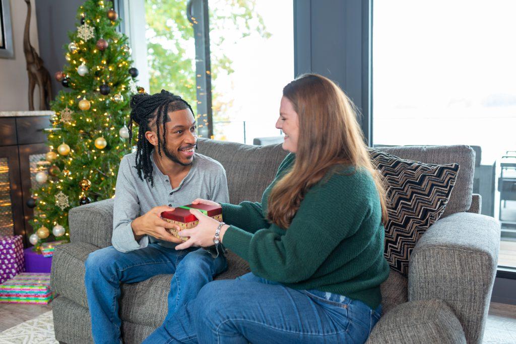 couple exchanging gifts in front of Christmas tree at a StayLakeNorman luxury vacation rental