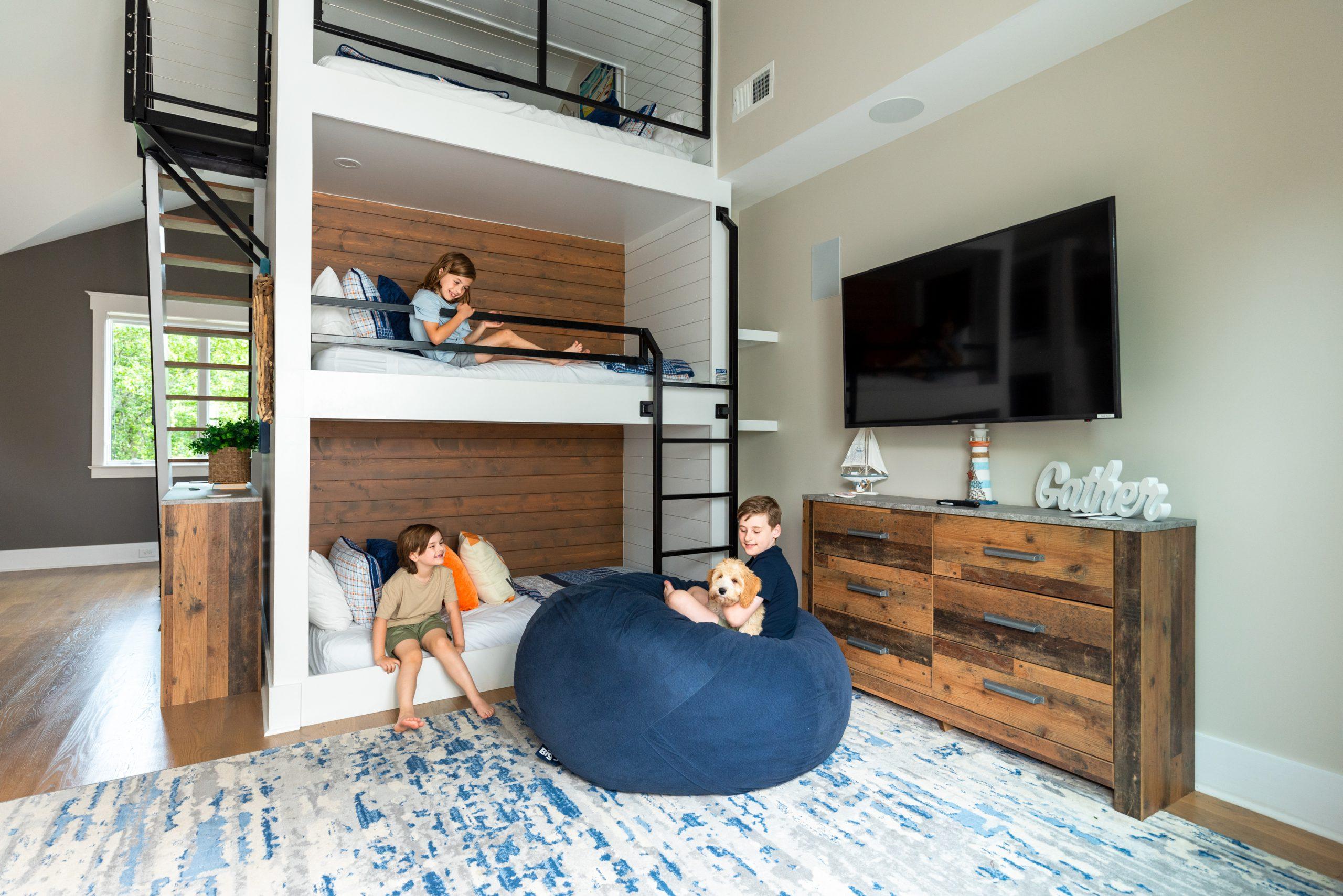 Three boys snuggle with dog in the custom bunk room at The Chasestone, a StayLakeNorman luxury waterfront rental in Lake Norman, NC. 