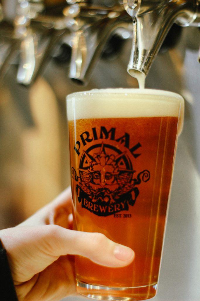 Primal Brewery craft beer glass being filled at the tap.